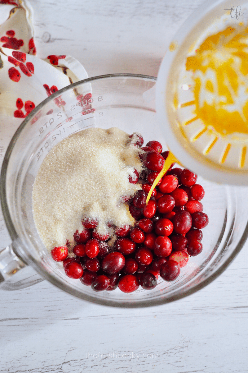 Adding sugar, cranberries and orange juice to mixture. 