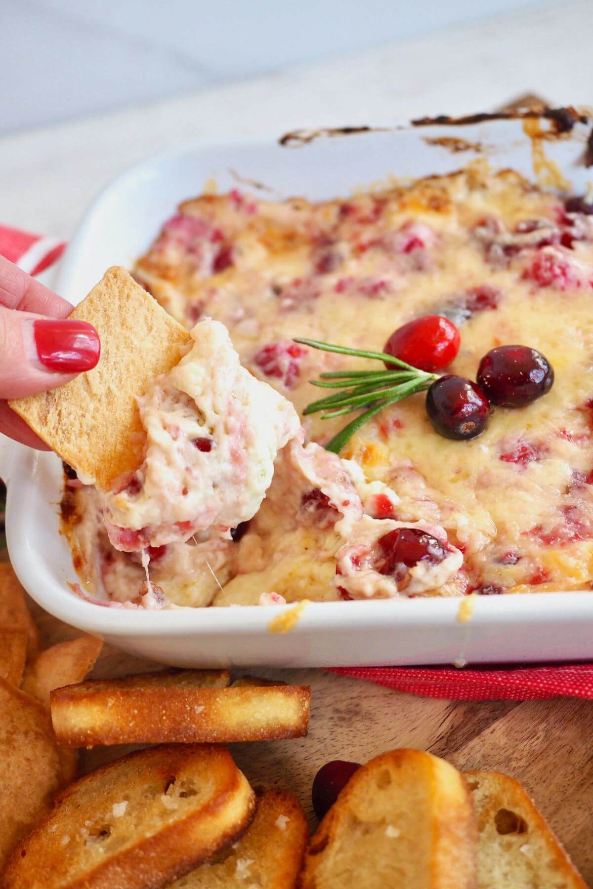 Dipping a pita chip into cream cheese cranberry dip. 