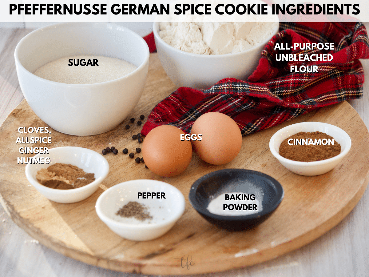 Ingredients for pfeffernusse German spice cookies L-R sugar, flour, cinnamon, baking powder, ginger, allspice, cloves, nutmeg and pepper plus eggs.