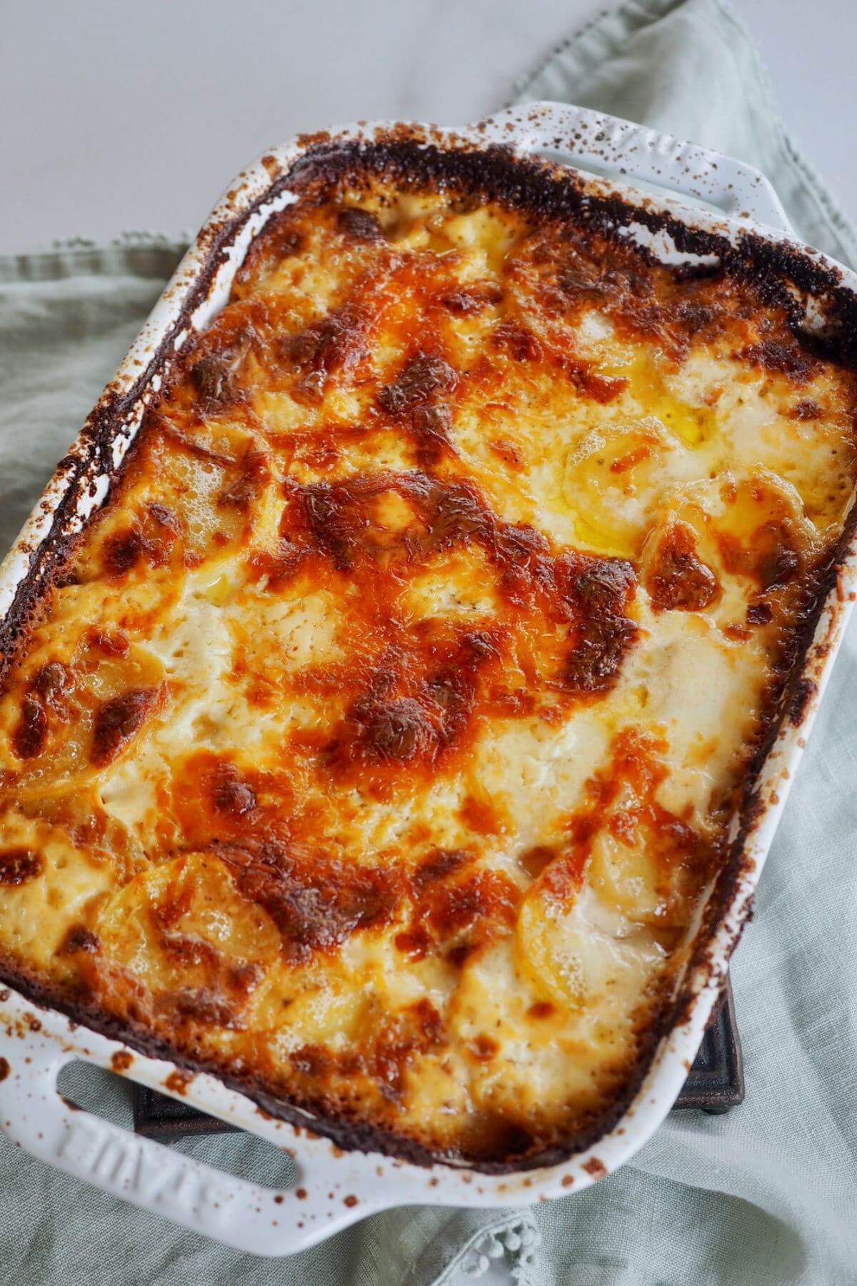 Casserole dish filled with golden and bubbly, cheesy potatoes au gratin.