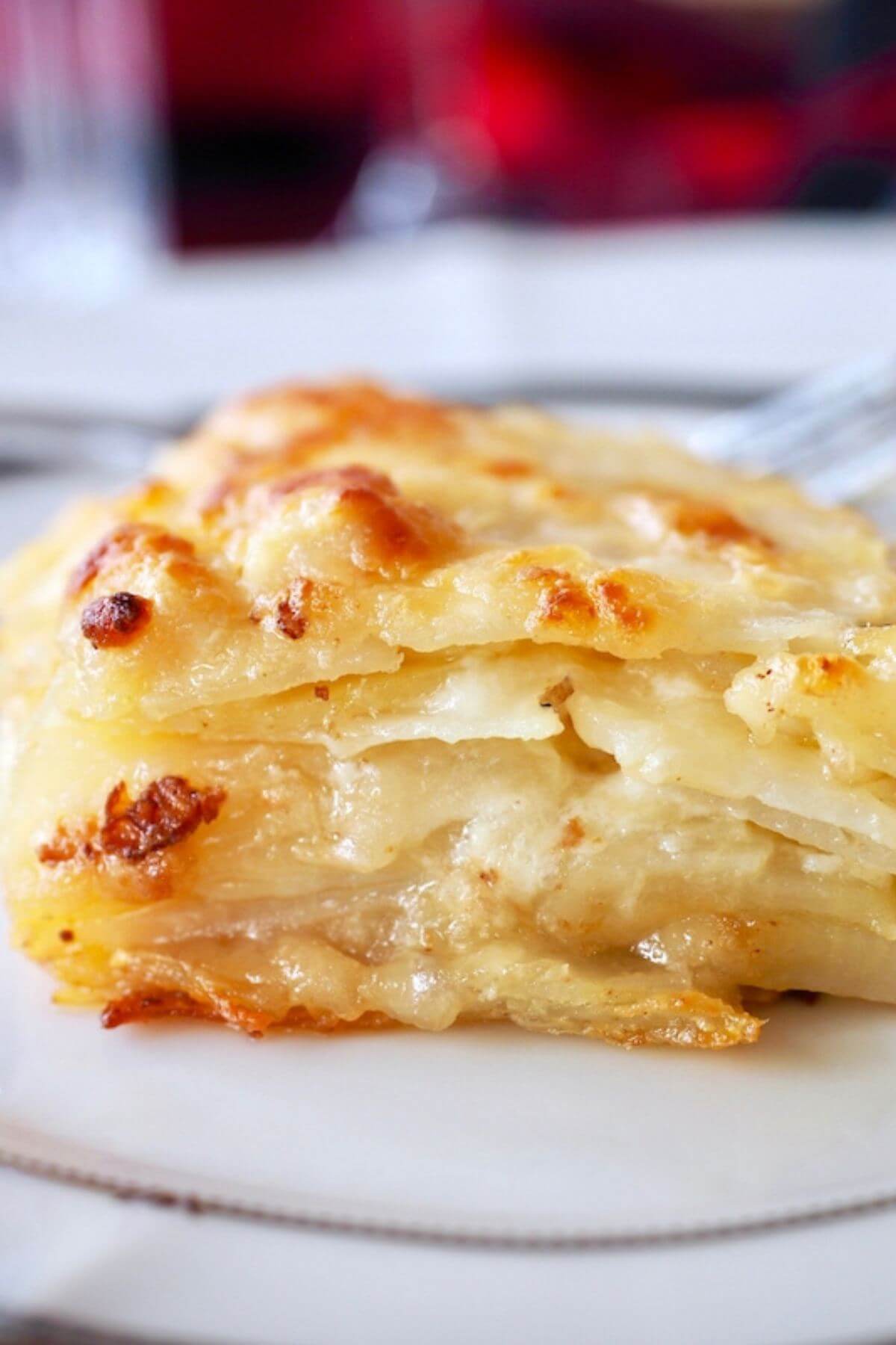 Layers of golden potatoes dauphinoise on a plate.