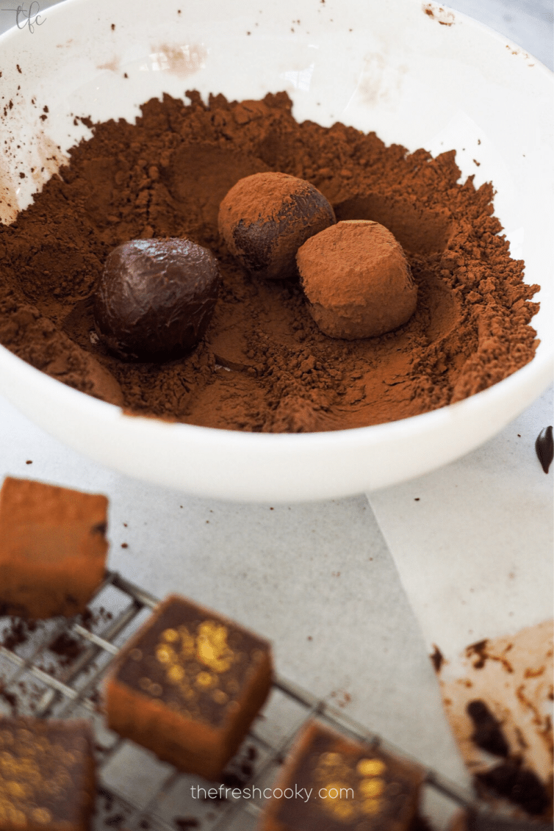 Rolling champagne truffles in cocoa powder.