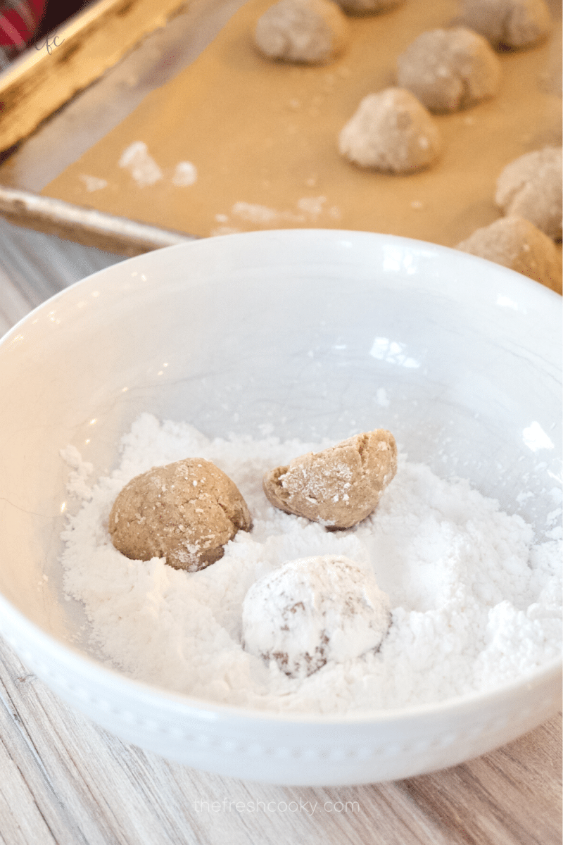 After cooling a few minutes, rolling baked cookies in powdered sugar. 