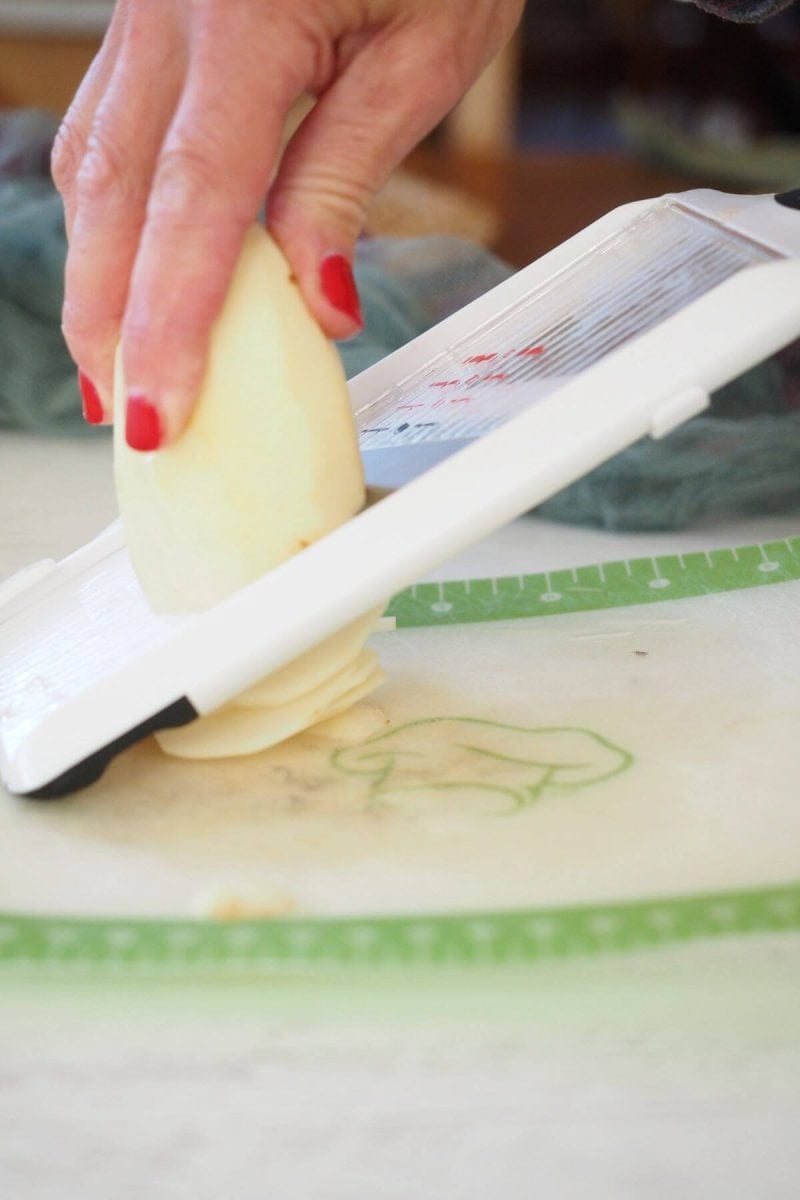Slicing a russet potato using a mandoline. 