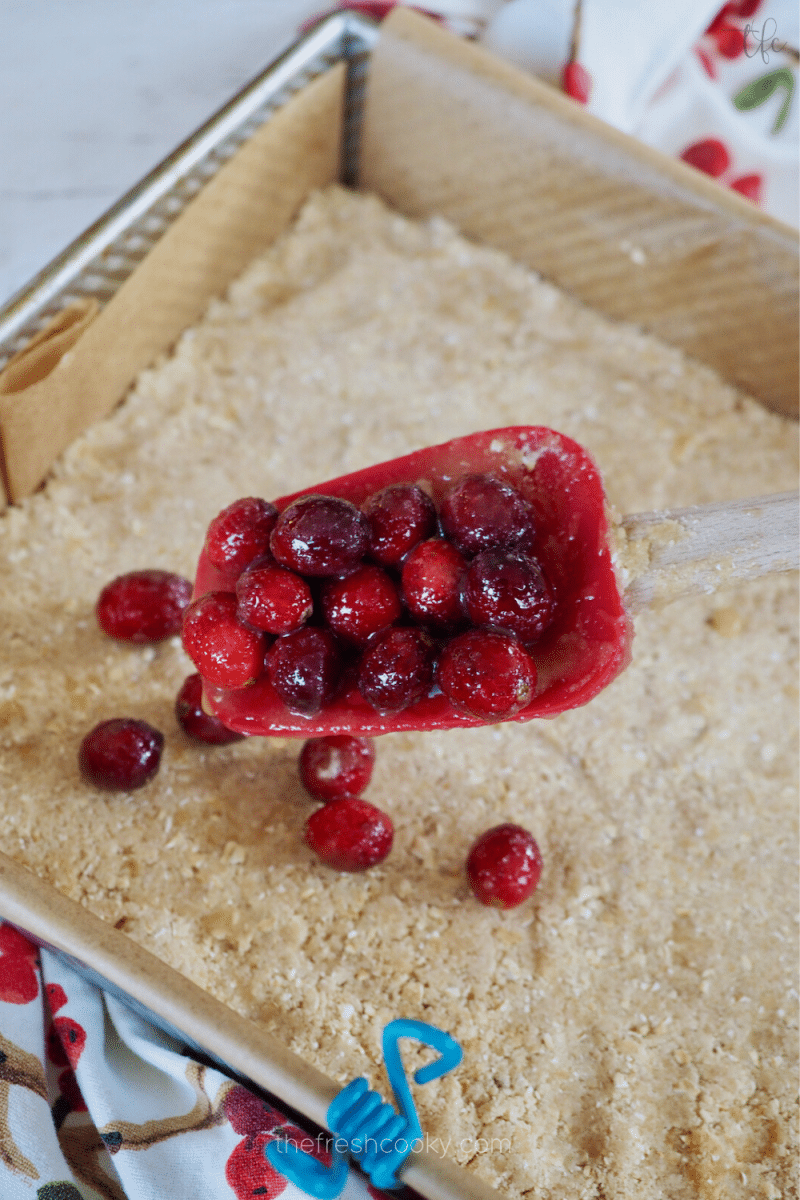 Spooning cranberry mixture over top of oatmeal crust. 