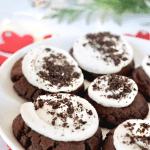 Holiday image of Copycat Crumbl Oreo Cookies with plate filled with frosted giant chocolate cookies.