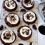 Giant Copycat Crumbl Oreo Cookies on a wire rack with frosting and Oreo crumbs around.