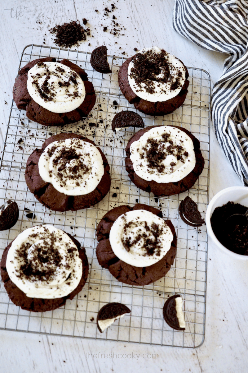 Giant Copycat Crumbl Oreo Cookies on a wire rack with frosting and Oreo crumbs around.