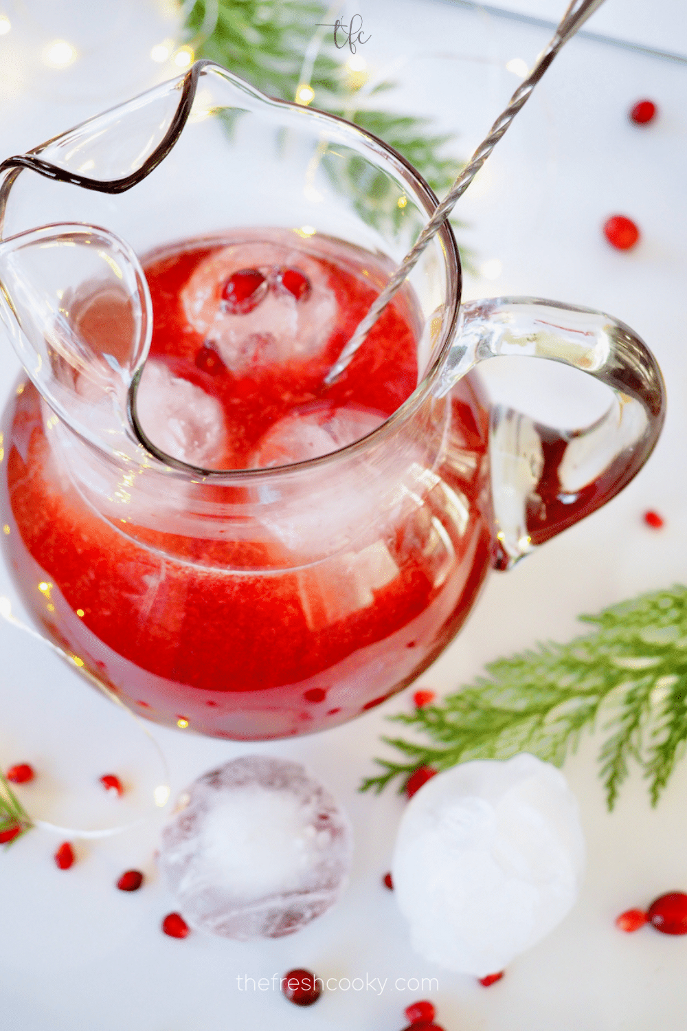 Pomegranate Vodka Punch in pretty glass pitcher, with three pretty ice cube balls inside. 
