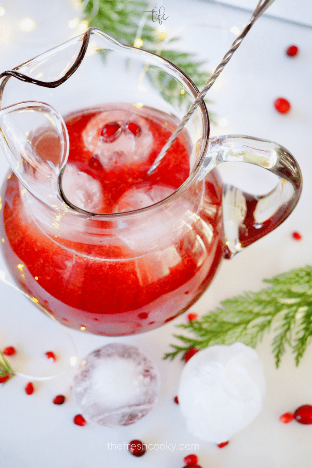 Pomegranate Vodka Punch in pretty glass pitcher, with three pretty ice cube balls inside.