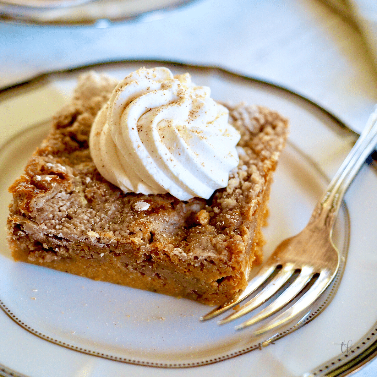 Easy pumpkin pie dump cake with square of cake on plate with a swirl of whipped cream, topped with fresh nutmeg.