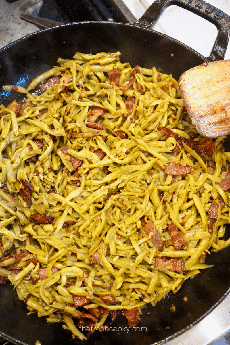 Stirring french green beans for southern style green beans with bacon. 