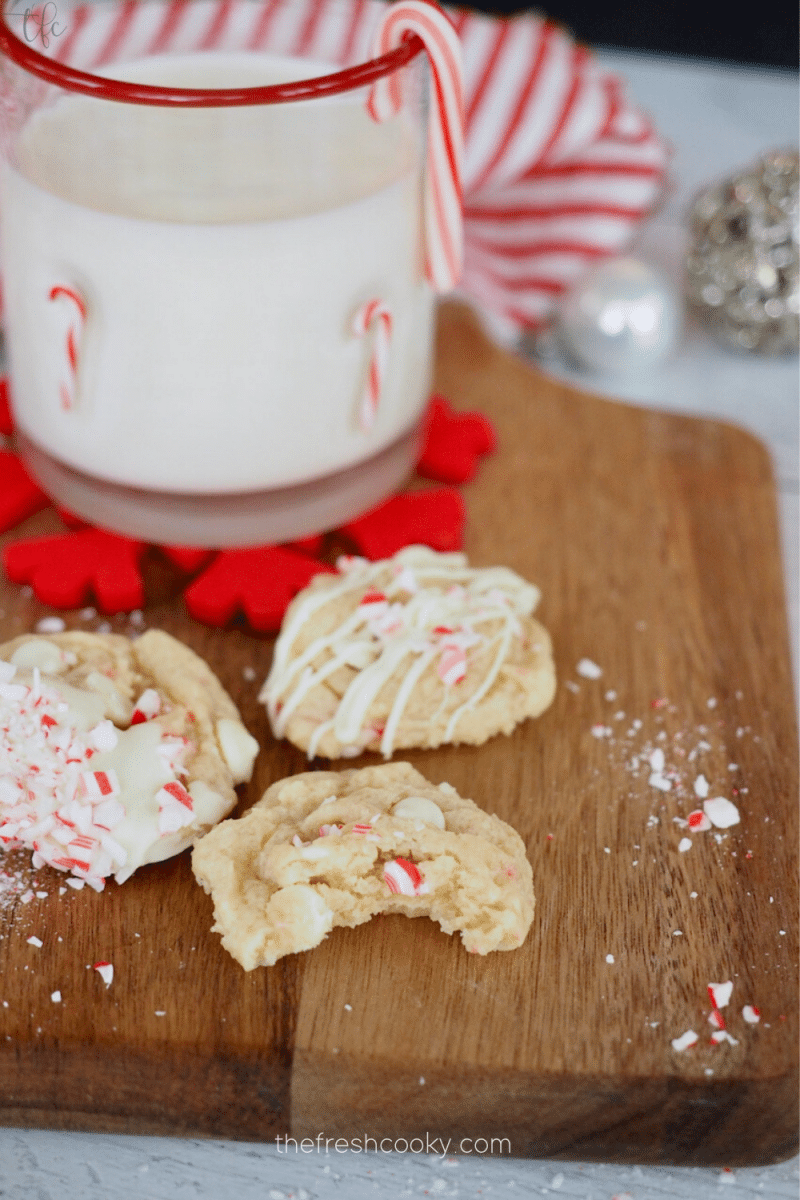 White Chocolate Chip Peppermint Cookies three ways on cutting board with milk in background.