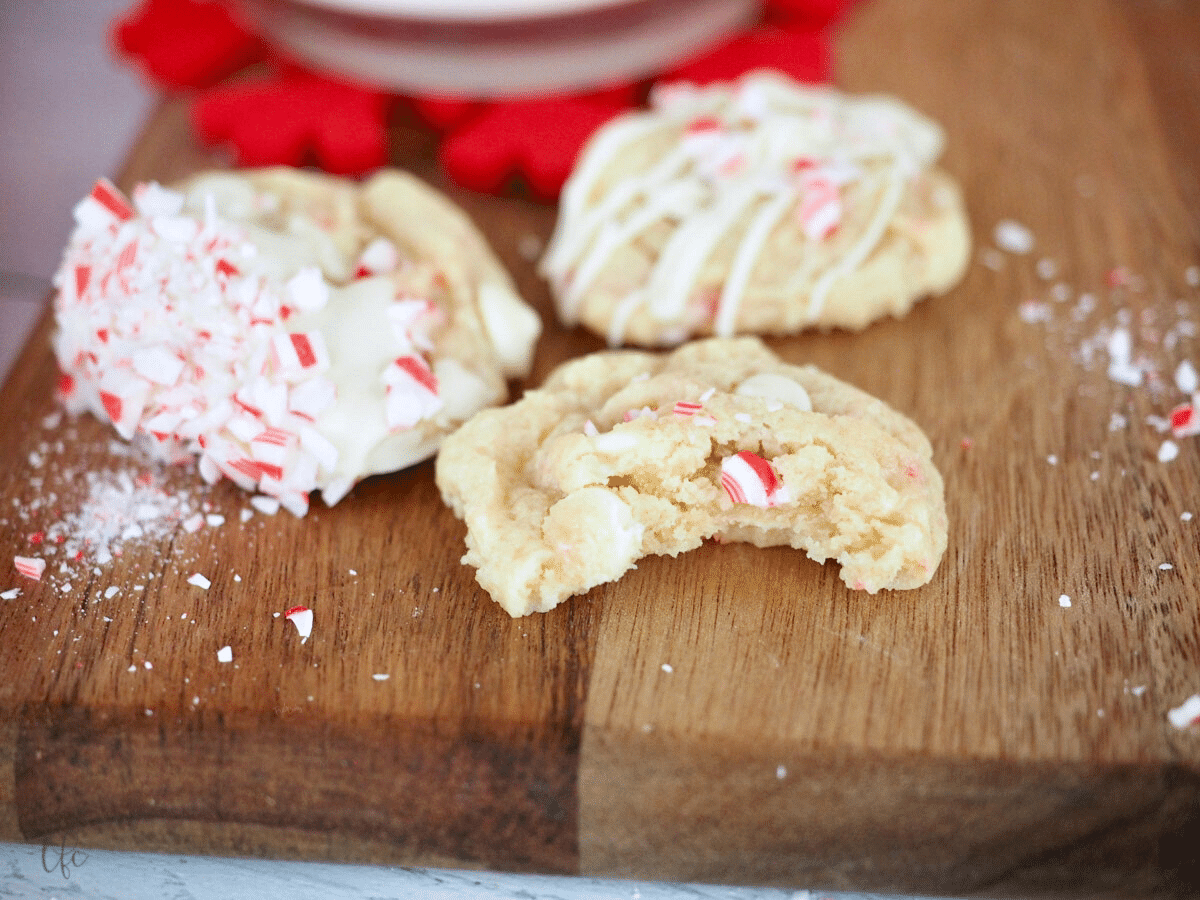 White Chocolate Peppermint Cookies on cutting board with bite taken out of a cookie.