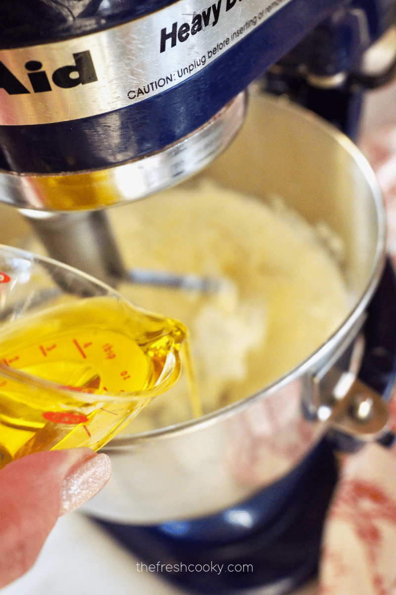 Adding olive oil and salt to whipped goat cheese mixture. 