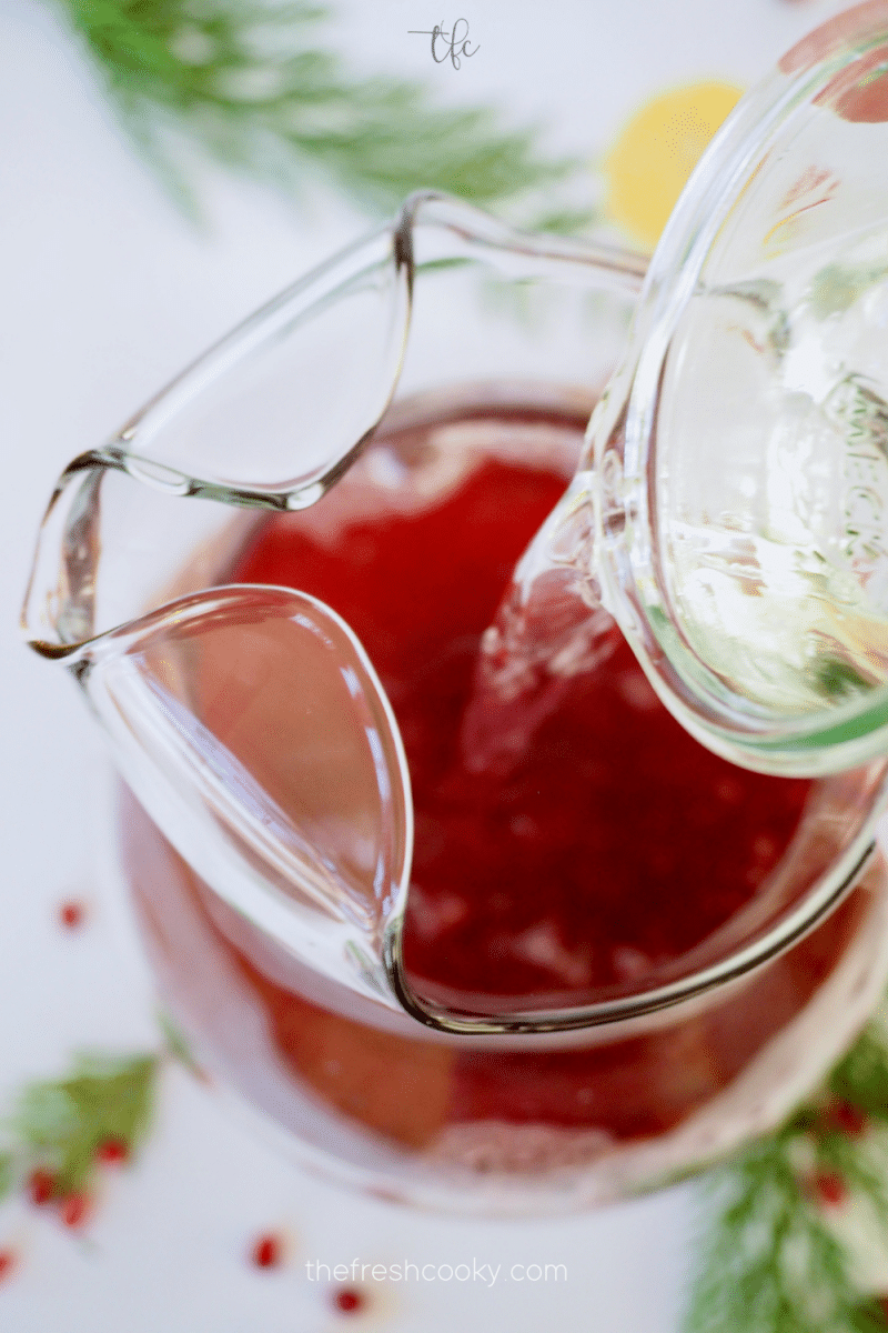 Adding simple syrup to pomegranate vodka punch. 