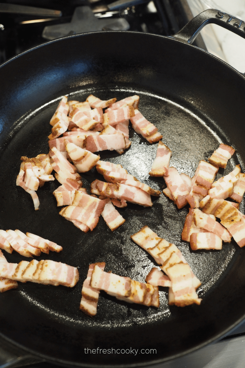 Bacon pieces crisp cooking in large skillet for green beans with bacon. 