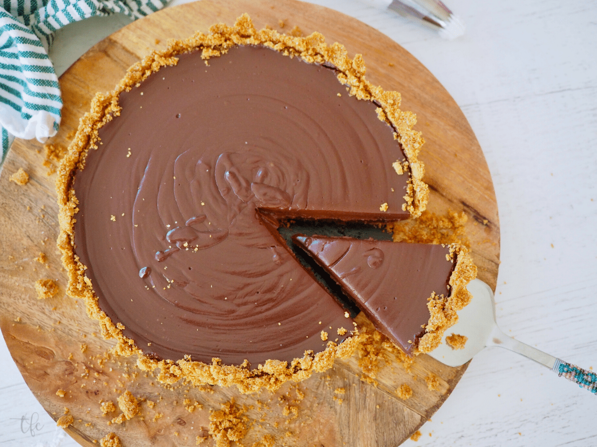 No bake chocolate pie in graham cracker crust on tray with wedge cut and slightly pulled out