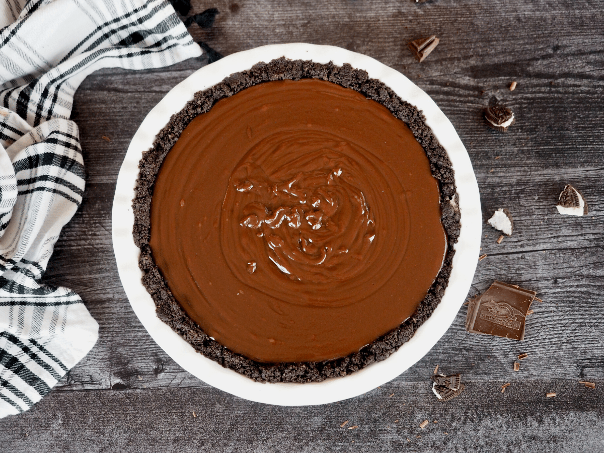 No Bake Chocolate pie with Oreo Crust on board with broken Oreos and chocolate.