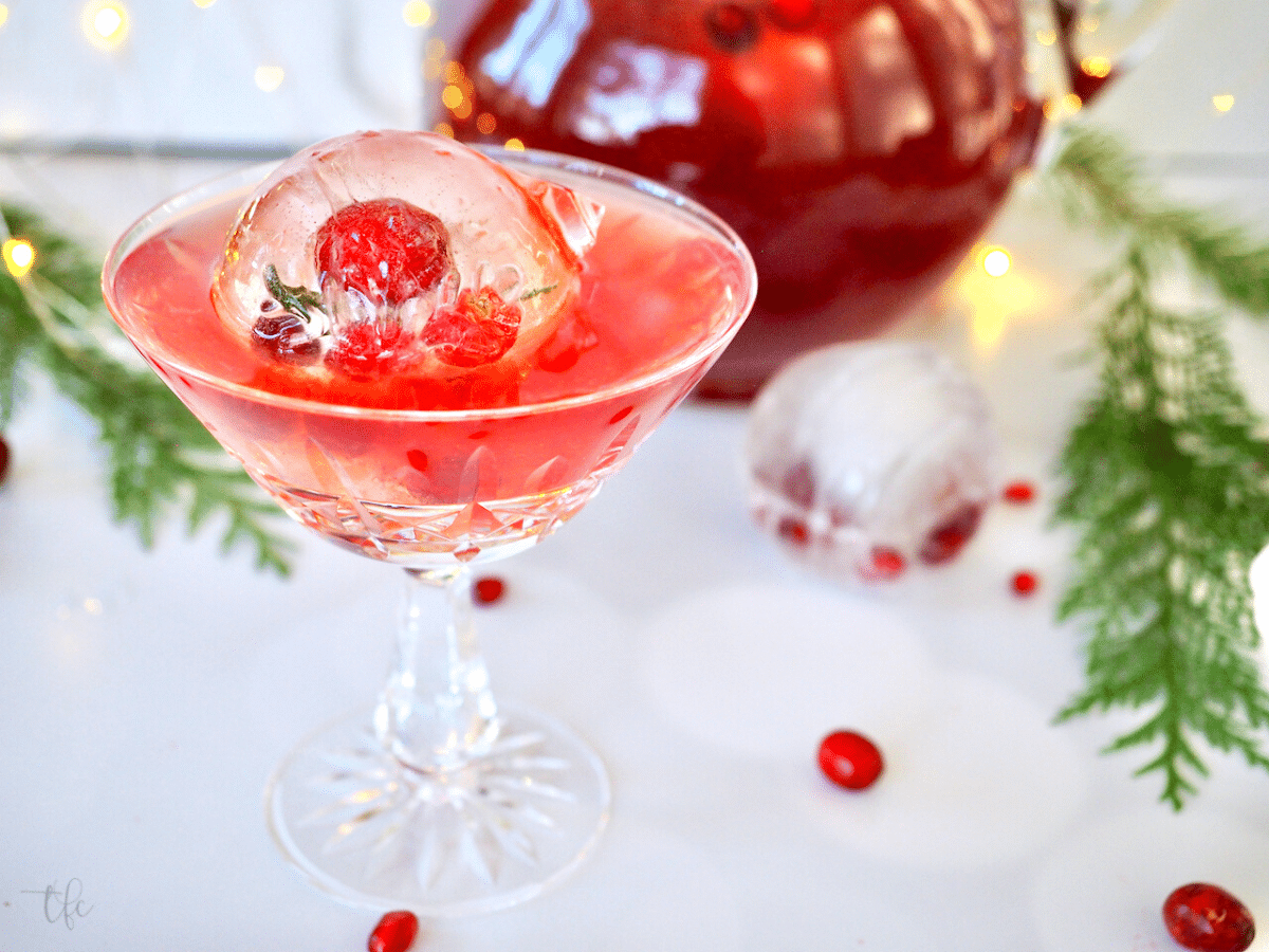 Pomegranate Vodka Punch in a pretty cocktail glass with a floating ball of ice.