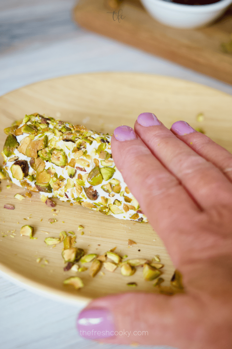Hand rolling goat cheese log in chopped pistachios.