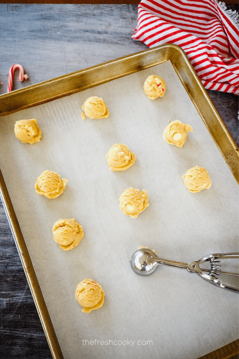 Cookie dough scooped onto parchment lined baking sheet for white chocolate peppermint cookies. 