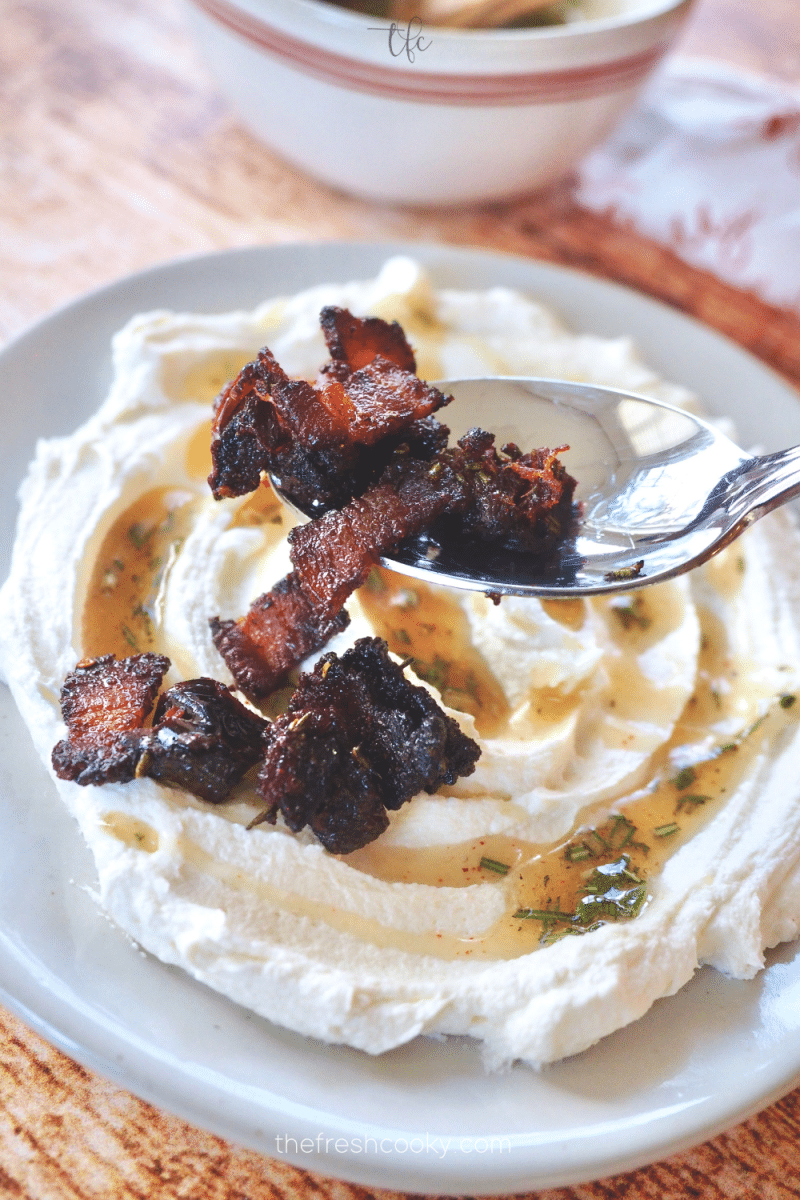 Spooning bacon and date mixture over goat cheese. 