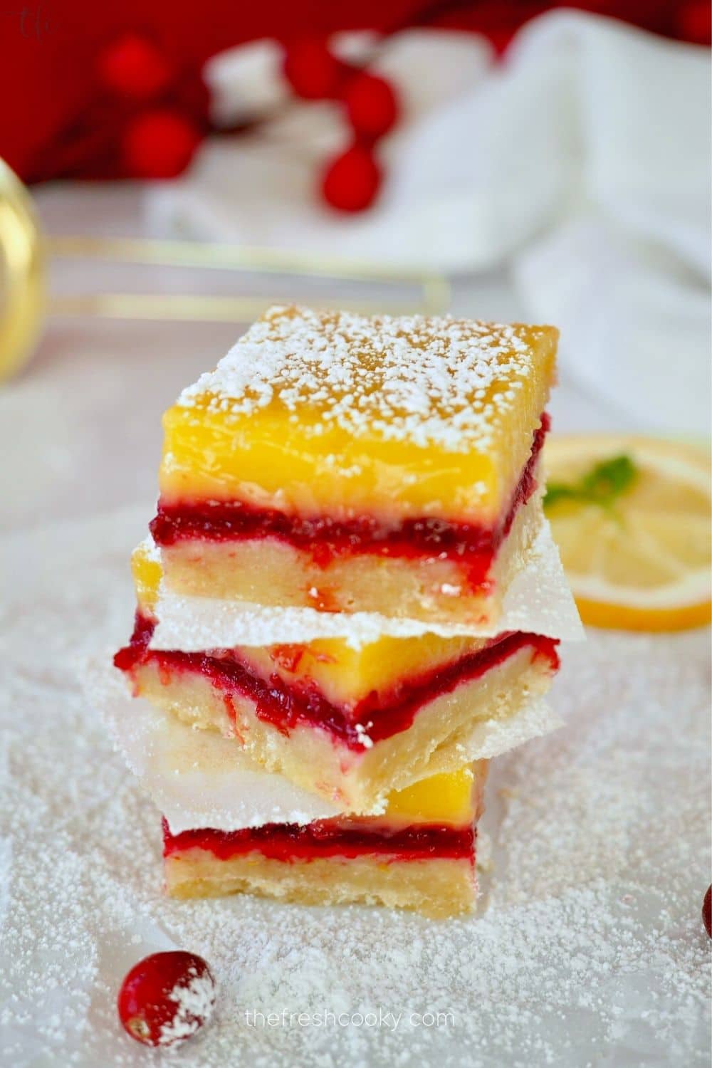 Lemon cranberry bars layered on top of each other, stacked 3 high with cranberries nearby.