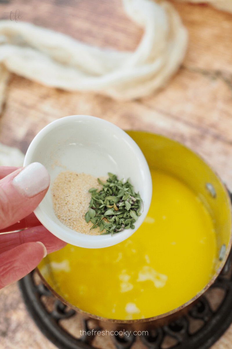 Adding onion powder, garlic powder and thyme to butter sauce for sliders. 