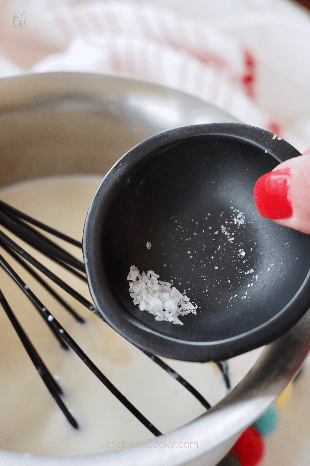Adding a pinch of flaky sea salt to white hot chocolate mixture.