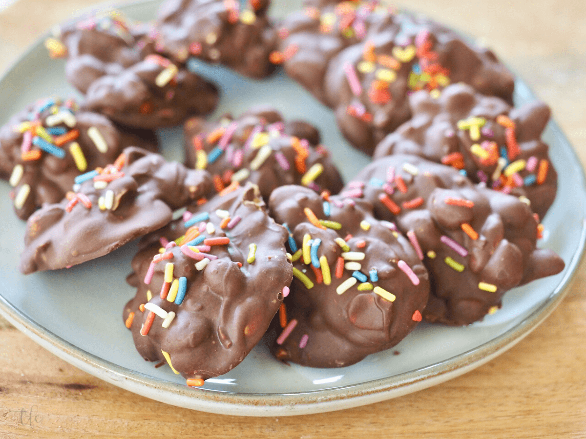 Easy slow cooker peanut clusters on a plate with rainbow jimmies on top.