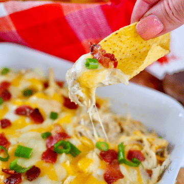 Square image for crockpot ranch chicken with hand scooping dip with tortilla chip.