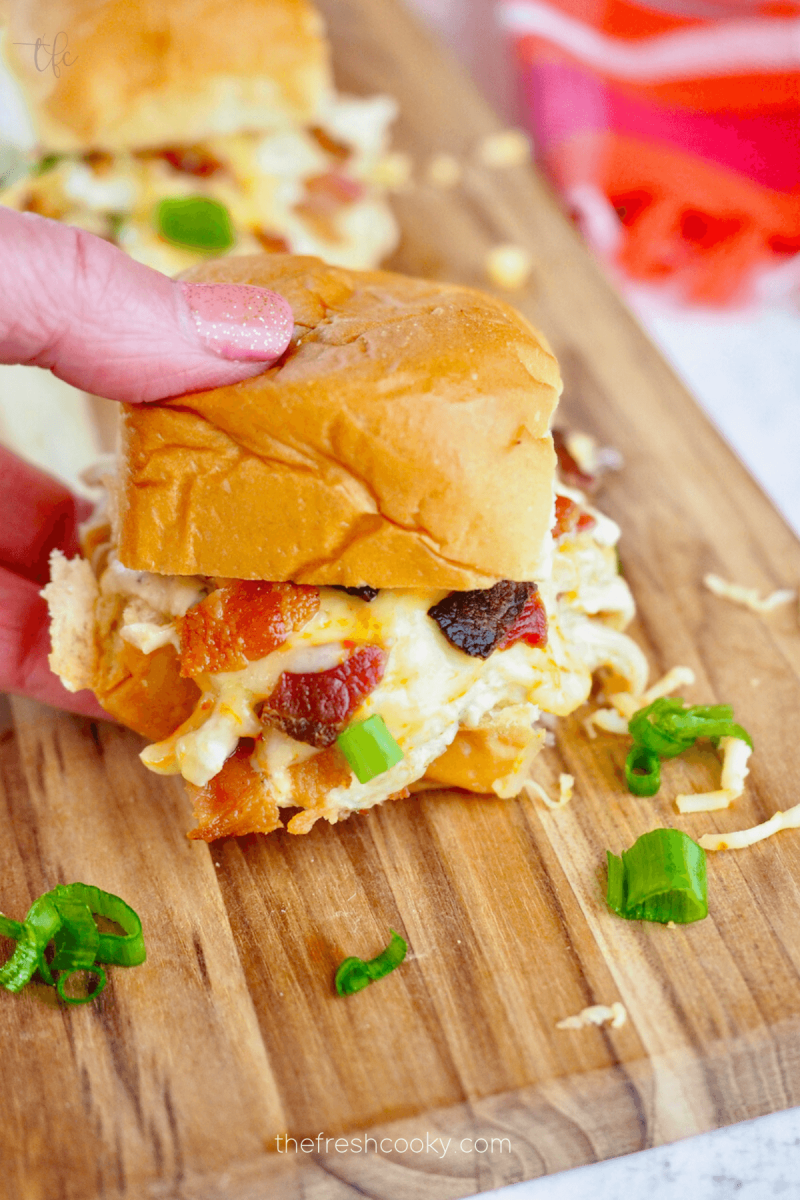 Hand grabbing a slider with filled with creamy crockpot ranch chicken.