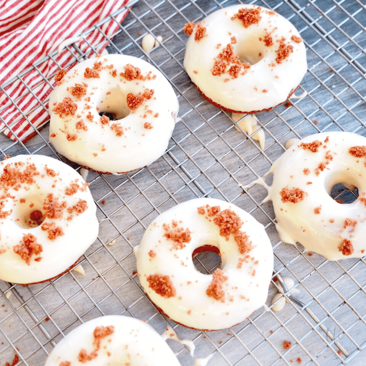 Red velvet donuts with glaze on wire rack.