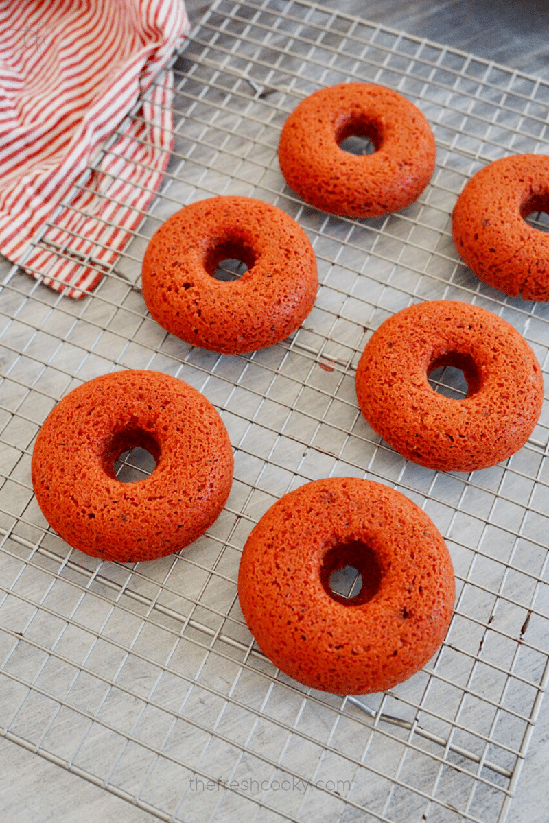 Cooling red velvet donuts on cooling rack. 
