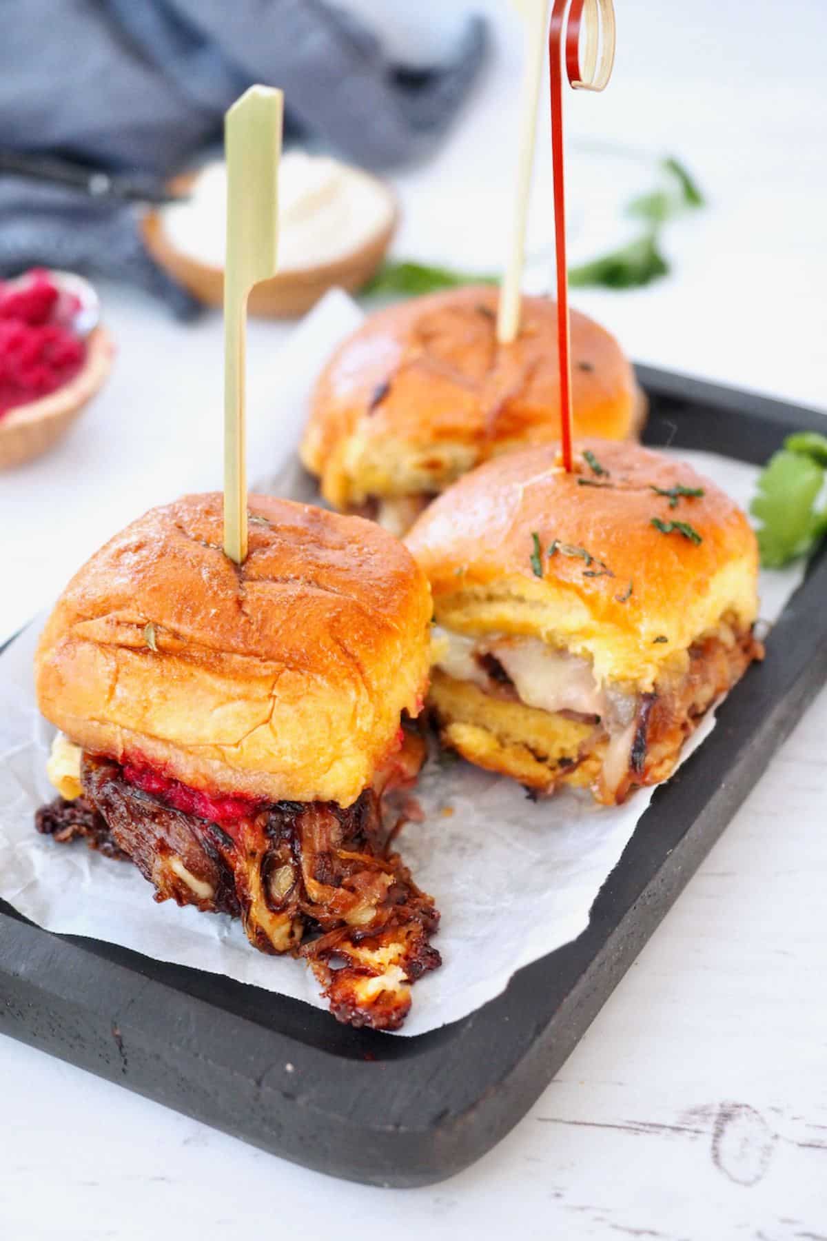 Roast beef sliders on a tray with picks, ready to grab.