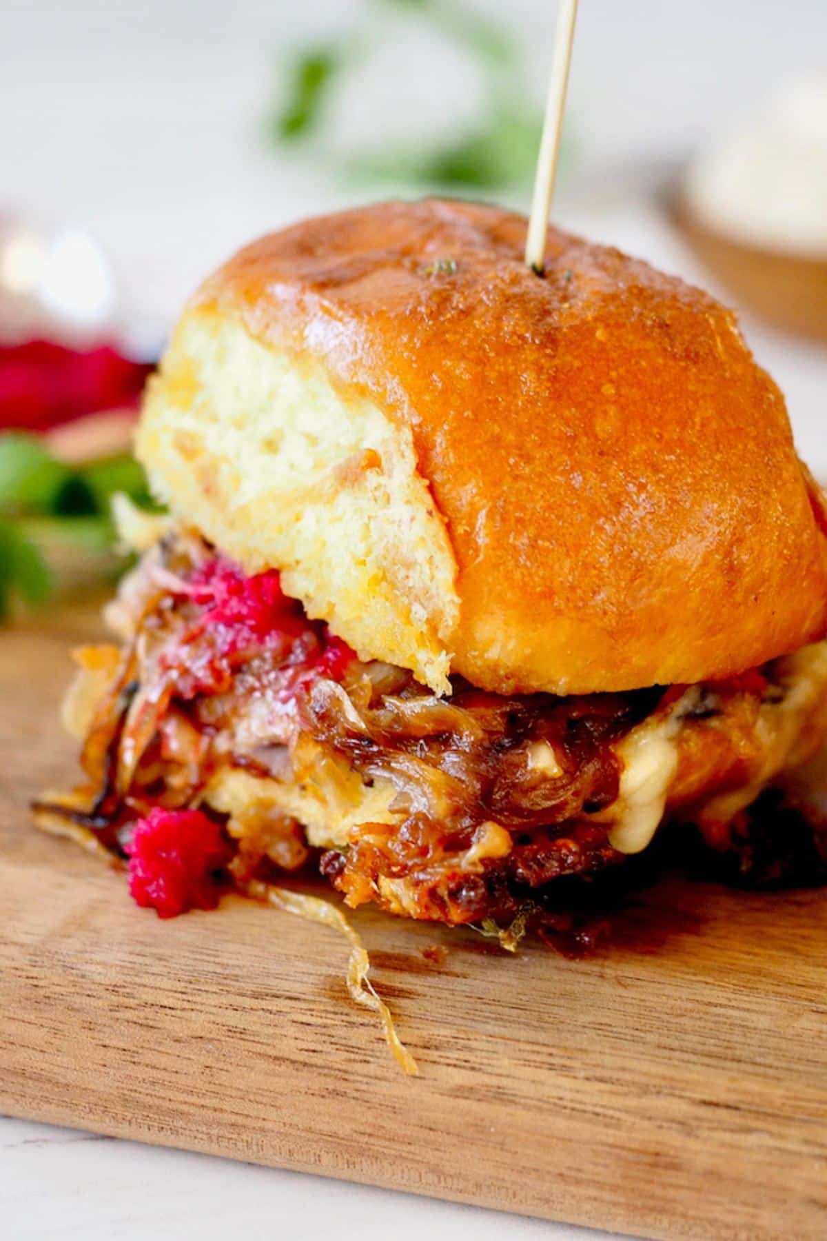 Roast beef slider on cutting board with beet horseradish oozing from the sides.