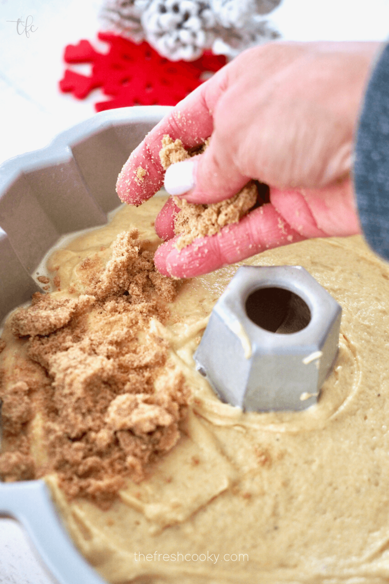Adding streusel topping to eggnog coffee cake batter.