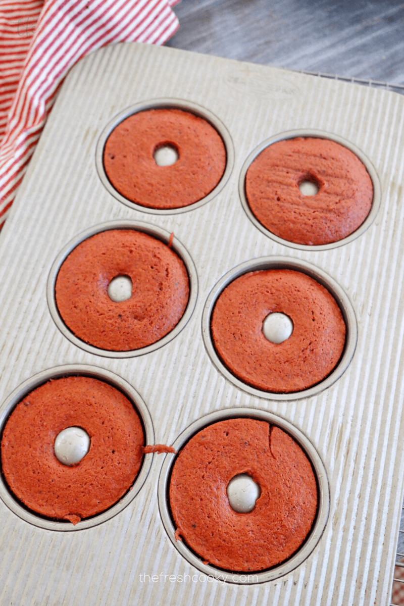 Baked red velvet donuts in donut pan, ready to flip. 