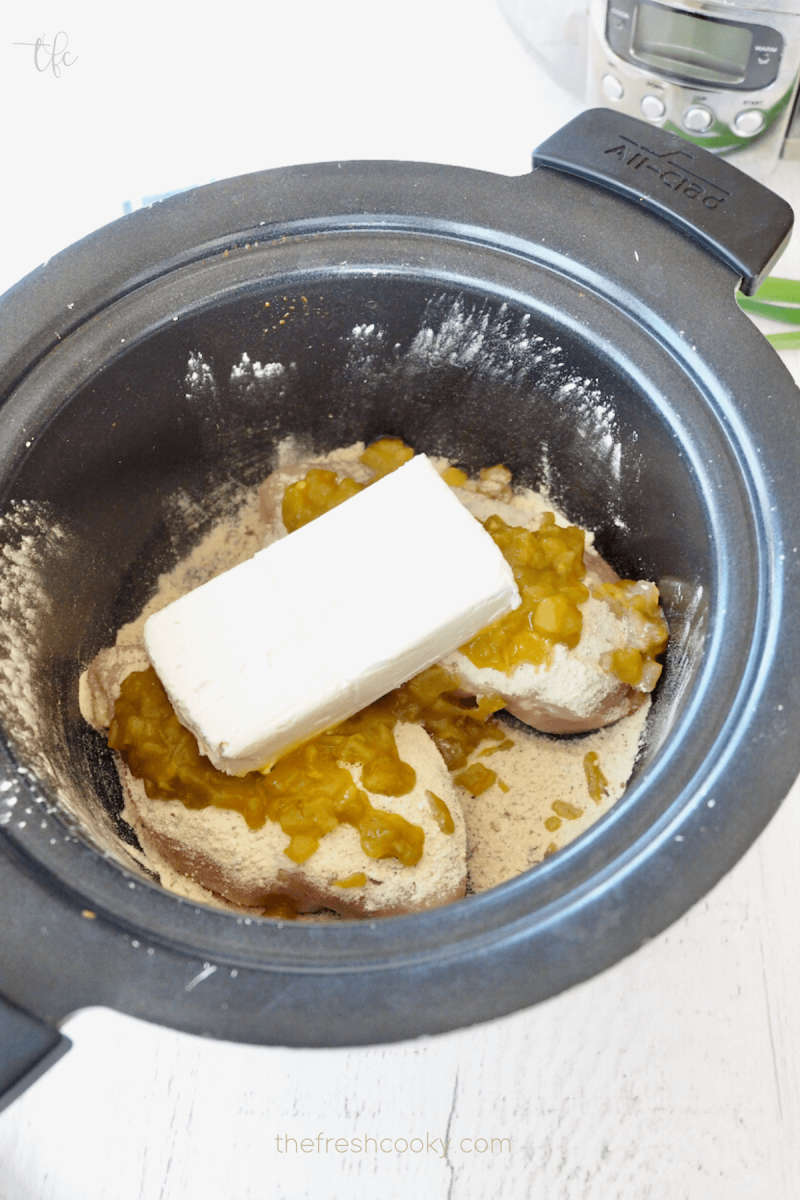 Block of cream cheese on top of chicken breasts in crock pot for Crockpot Ranch Chicken. 