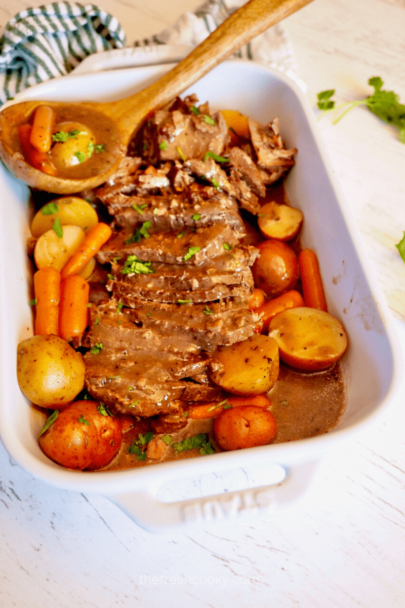 Crockpot London Broil in baking dish with carrots and potatoes and a thick gravy. 