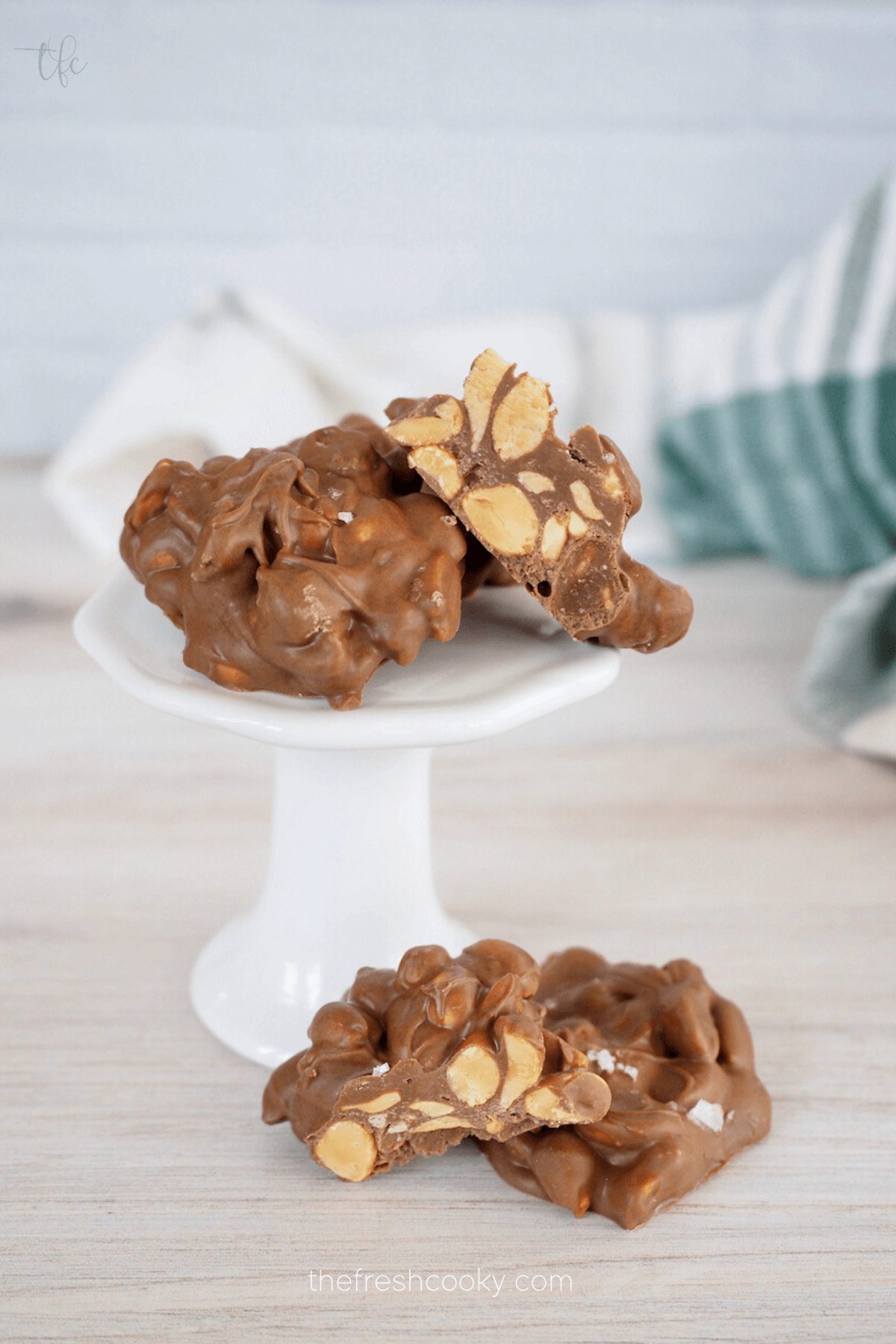 Best crockpot peanut clusters on pedestal with cluster cut in half.