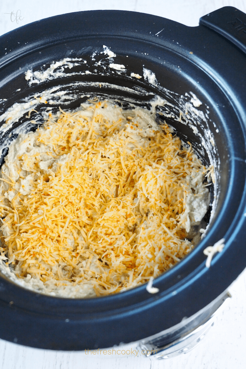 Add shredded cheddar cheese on top of shredded chicken mixture for Crockpot Ranch Chicken. 