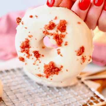 Red Velvet Donut being held in hand with delicious cream cheese glaze.