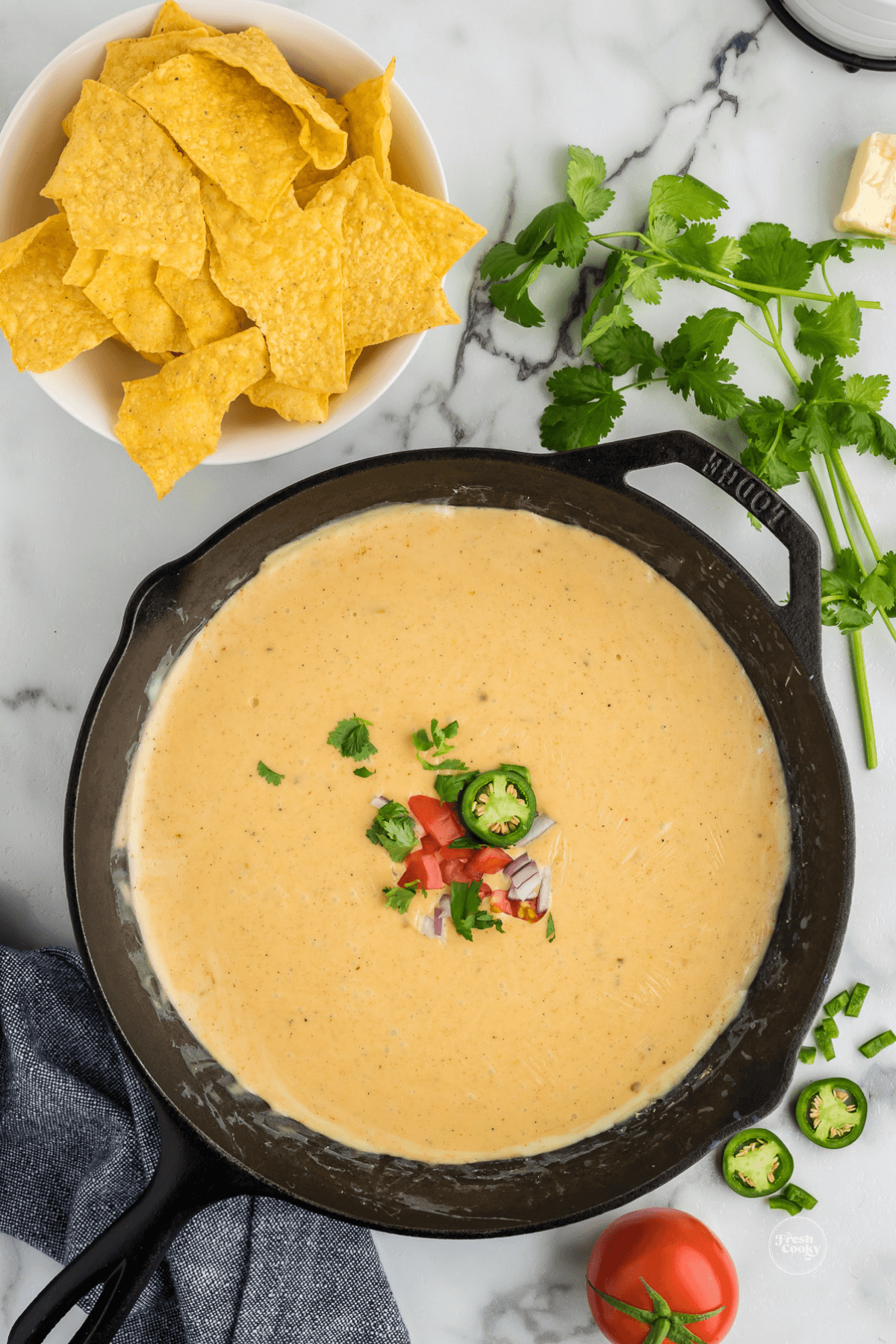 Ready to serve easy queso recipe without velveeta in cast iron pan with tortilla chips for dipping.