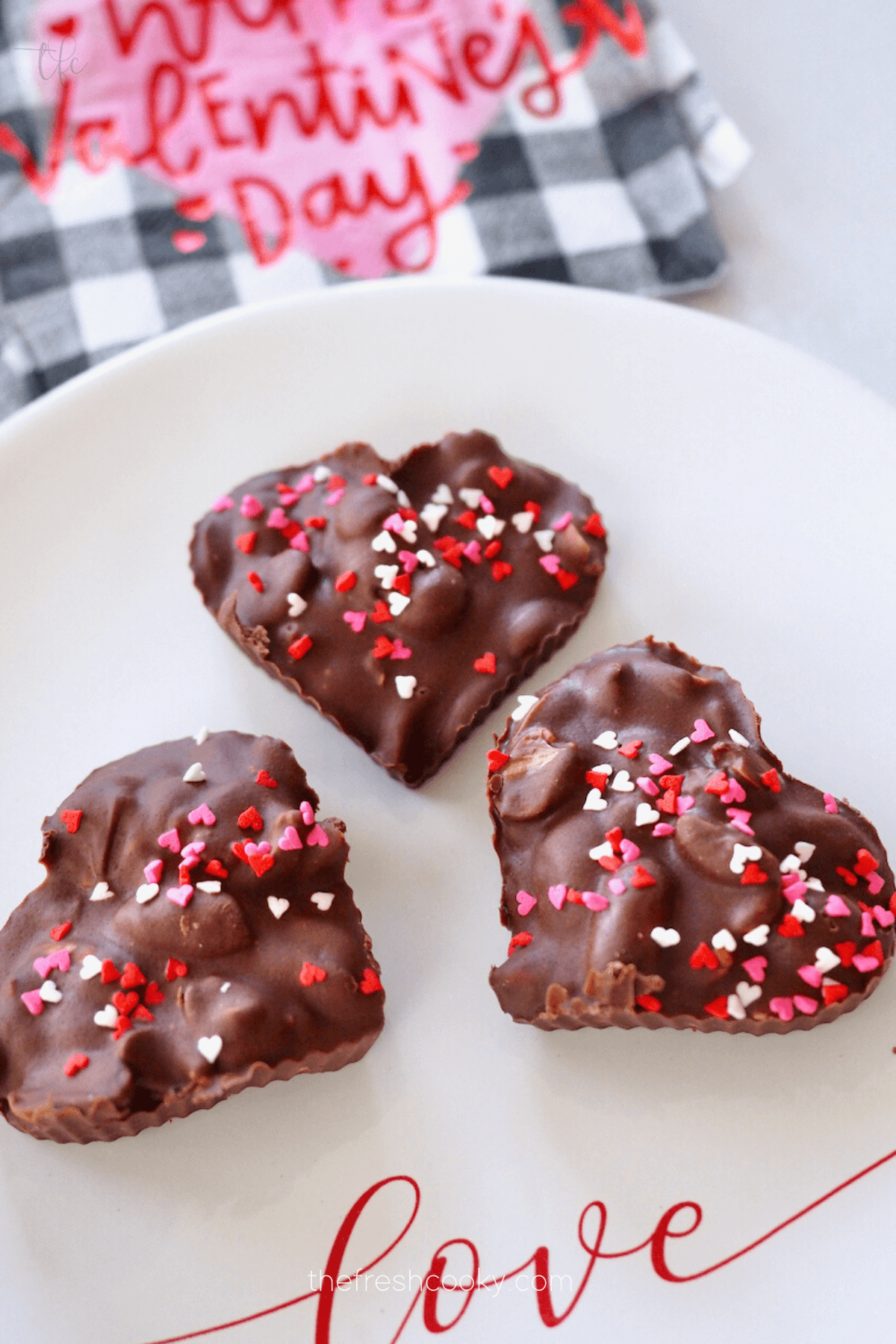 Pretty heart shaped crockpot peanut clusters on love plate for Valentine's day.