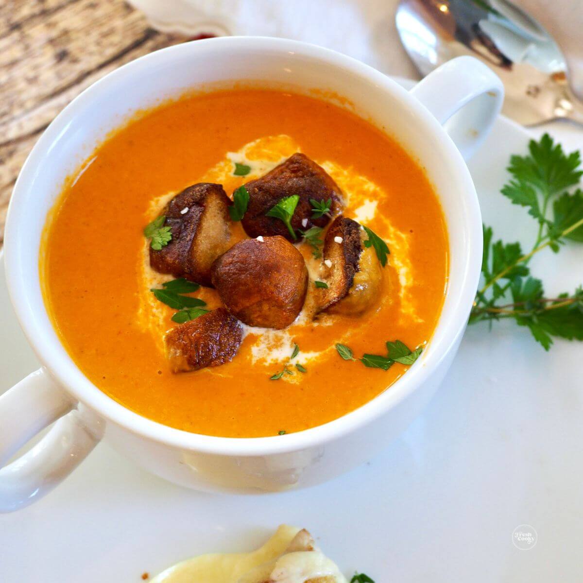 Creamy homemade tomato bisque in bowl with pretzel croutons.