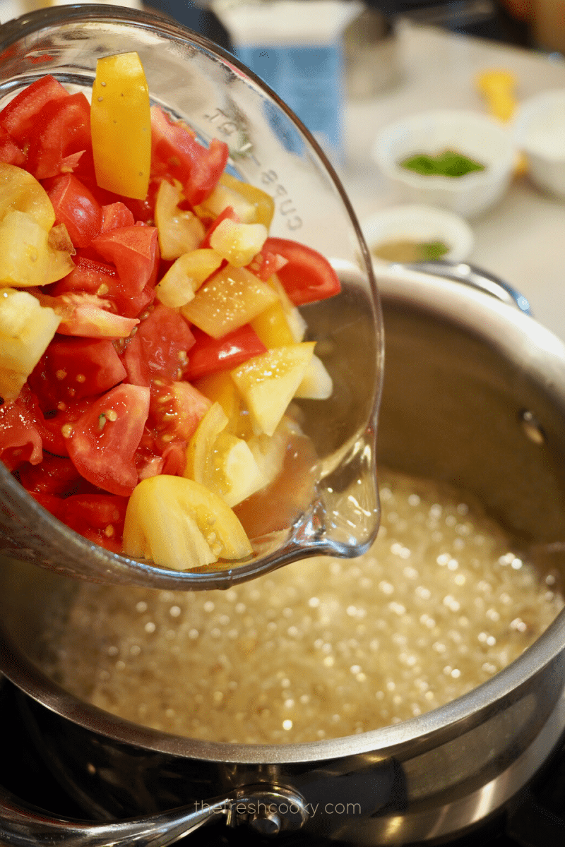 Pouring fresh cut tomatoes into saucepan for creamy tomato bisque recipe.