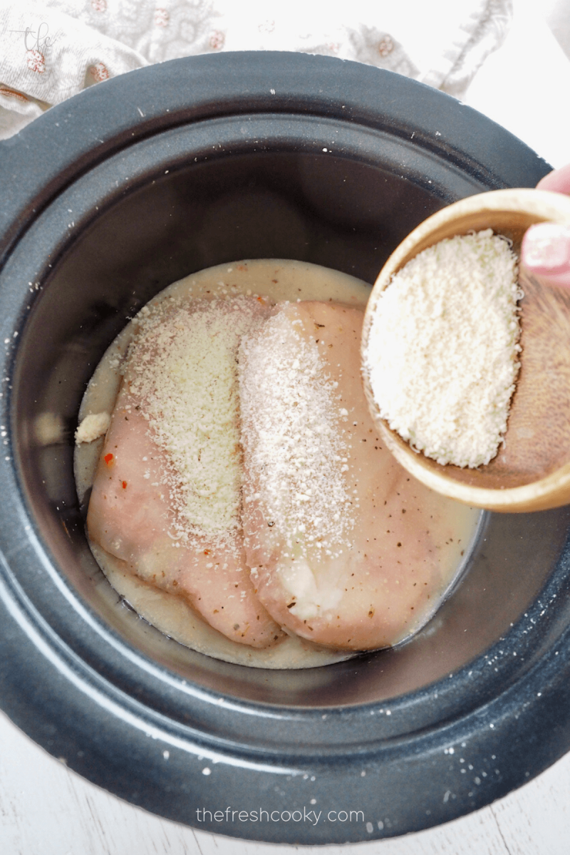 Sprinkling parmesan cheese over chicken for Olive Garden Chicken. 