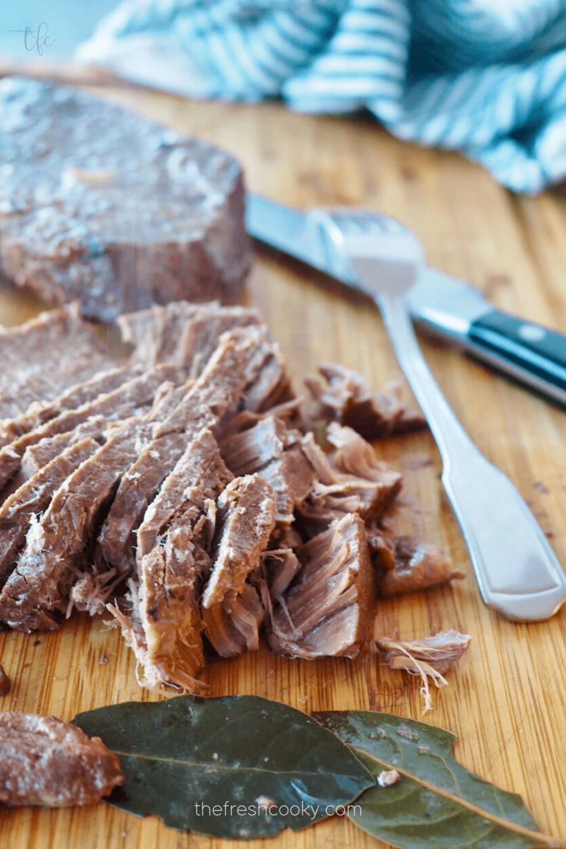 Slicing London Broil beef against the grain, with removed bay leaves. 